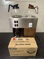 Front view of coffee brewer with two decanters on top and unopened filter box