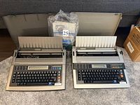 Both Panasonic electronic typewriters with lids removed, manual and ribbon pack visible