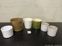 Front view of six ceramic plant pots lined up