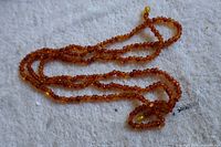Close-up view of the amber-colored beaded necklace showing the texture and color of the beads along with the clasp bead.