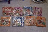21 small packets of worldwide stamps laid out on floor, each packet contains multiple stamps labeled by country or region
