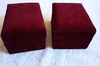 Two closed burgundy velvet boxes containing the napkin rings.
