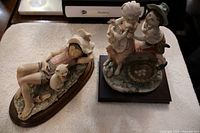 Two Capodimonte porcelain sculptures on wooden bases, photographed together to show scale and detail.
