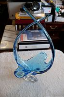 Front and full view of the blue Chalet art glass sculpture showing its abstract flowing design, clear base, and blue textured glass body.