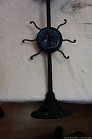 Full view of the decorative glass sun face attached to the black metal stand's rod, showing the facial features and sun rays.