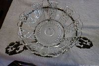 Top view showing the clear cut glass bowl with geometric patterns and the elaborate brass handles and base.