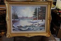 Large oil painting with snow-covered landscape including trees and river in an old gold frame.