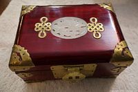 Front angle showing brass lock, brass corner reinforcements, and translucent carved oval panel