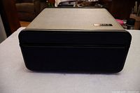 Front view of Sony reel to reel tape recorder closed in its beige fabric case with black trim and speaker grill.