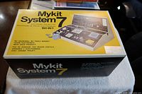 Photo of the full kit in original box with front and top views showing Mykit System 7 150-in-1 electronic project kit.