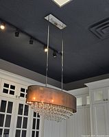 View of the oval chandelier hanging in a showroom with sheer black shade and clear globe crystals underneath