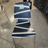 Top view of black chair with white diagonal stripes on seat and backrest, single chair shown in showroom.