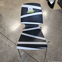 Top view of black chair with white diagonal stripes on the seat and backrest, showing the graphic pattern and condition.