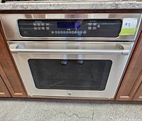 Front view of stainless steel GE Café built-in convection wall oven installed in cabinetry.