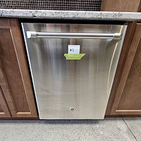 Front view of dishwasher installed in cabinetry showing stainless steel full-height door and tubular handle.