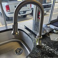 Full view of the faucet mounted on a granite countertop showing the brushed nickel finish and the single lever handle.