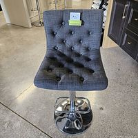 Front view of the adjustable grey fabric bar stool showing tufted button upholstery.