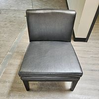 Front view of the grey leatherette lounge chair showing wide seat and cushion detail