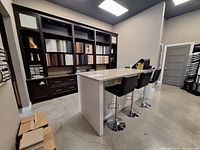 Wide view showing dark brown display cabinets with laminate countertop and cream island with quartz top