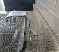 Chrome waterfall style vanity faucet installed on countertop with clear textured glass sink.