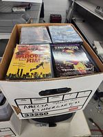 Top view of banker’s box showing multiple DVD stacks; titles Above the Rim and Terminator 2 visible