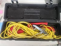 Open black plastic box showing yellow rope, red strap and chain saw components