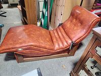 Side view of brown faux leather motorized chaise showing curved shape and wood base