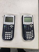 Front view of both TI-84 Plus calculators powered status visible