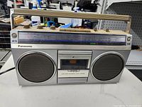 Front view of Panasonic radio cassette recorder showing speakers, cassette deck, tuning scale, handle