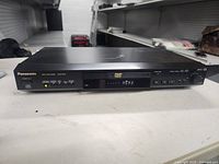 Front view showing Panasonic branding, display, buttons, rotary knob