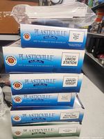 Stack of Plasticville O scale kit boxes showing titles Signal Bridge, Union Station, Airport Hangar, Rural Two-Story House and one additional box