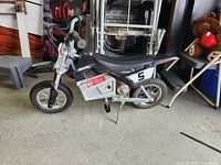 Left side view of Razor electric minibike showing full body, number 5 graphic, kickstand down