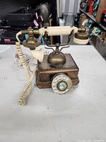 Front view of brass-tone rotary dial telephone showing handset, cradle and dial