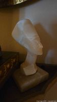 Side angle of alabaster Nefertiti bust showing profile and headdress details.