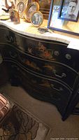 Front and side view of the black curved front dresser with Asian motif decorations and marble top.