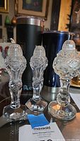 Three crystal cut glass pieces displayed together showing two matching tall salt and pepper shakers and one larger third shaker with rounded body and pedestal base.