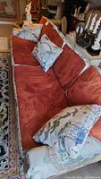 Full view of eight-foot sofa showing red suede cushions and printed fabric upholstery with matching pillows