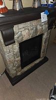 Electric fireplace showing front view with faux stone mantel and dark wood mantel shelf with corbels