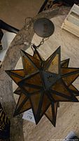 Photo of the amber glass panel hanging star light on a table showing its metal frame and hanging chain.