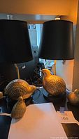 Two Mid Century Modern brass partridge lamps with black shades and two smaller brass partridge figurines on a table.
