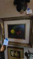 Front view of matted and framed oil painting depicting a yellow lemon and three strawberries on a dark background.