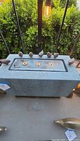 Front view of rectangular grey speckled fountain showing three recessed LED lights and multiple bird figurines perched on the top edge