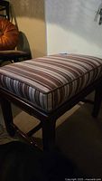 Bench showing side and top view of padded seat with striped fabric.