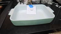 Front angled view of the rectangular green Pyrex casserole dish showing the white interior and integrated handles.