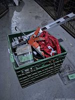 Crate with assorted hand tools including a level, caulking gun, gloves, and various supplies.