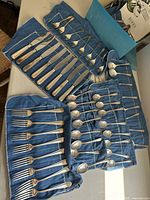 Entire set of flatware displayed in original Birks box with fabric rolls