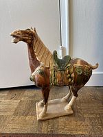 Side profile of ceramic horse showing detailed ceramic saddle, mane and posture on rectangular base.