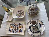 Overview of 8 painted ceramic servingware pieces on table including trays, bowl, teapot, and pitcher