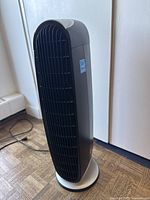 Side view of the tall, tower-style black and gray Honeywell air purifier showing its curved shape and power cord.