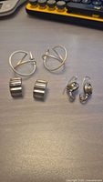 Three pairs of vintage sterling silver earrings displayed on a table: wire hoop earrings, ribbed clip-on earrings, and oval drop earrings.